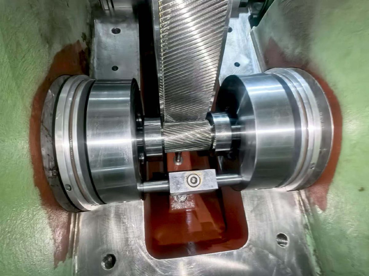 Cameron TA6000 overhaul — pinion shaft and bull gear meshing inside the opened gearbox with lube oil nozzle