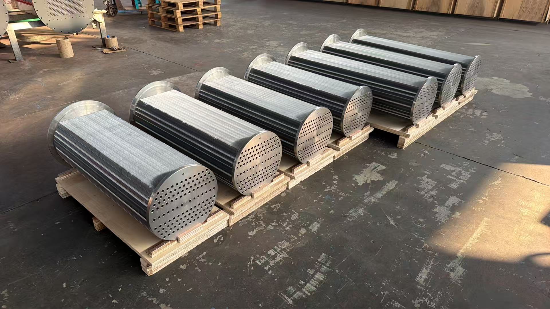 High-angle view of a batch of Atlas Copco ZH560 aftercooler bundles arranged in rows on the floor at Turbomax, showing the circular tube sheet ends ready for final pneumatic seal test before export packing to India