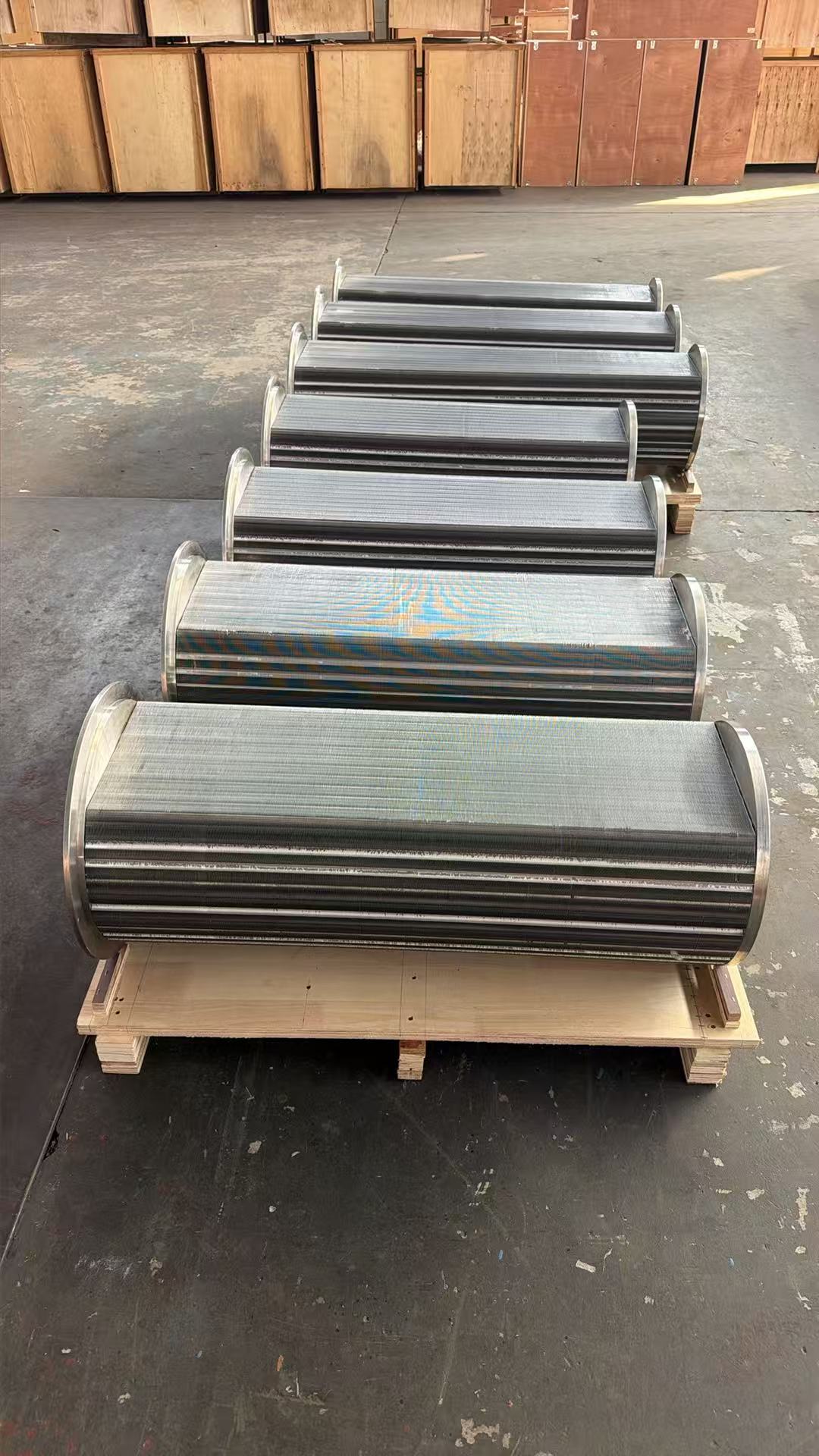 Rear view of the production line showing the second row of Atlas Copco ZH560 cooler bundles at Turbomax, with finished bundles wrapped and ready for export packing after passing all three QC stages
